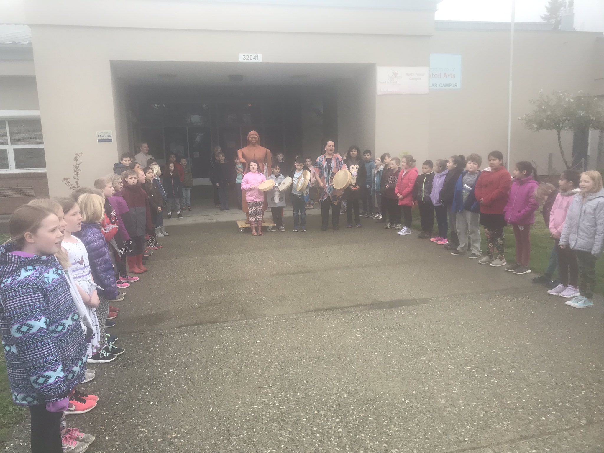 Students welcome a guest by the Sto:lo Welcome Post