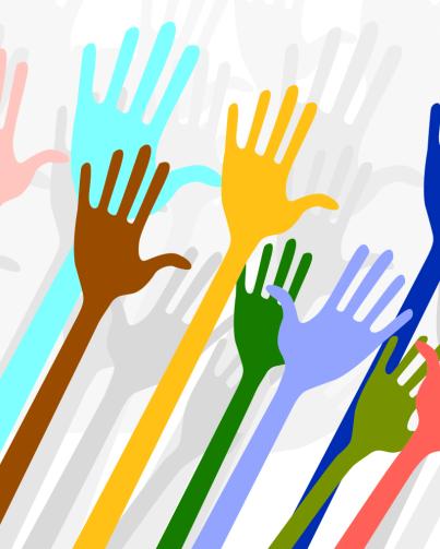 simple illustration of many different coloured hands being held up in the air, volunteering. The hands in the foreground are all different bright colours. The hands in the background are shades of light grey